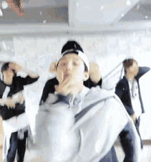a group of people are dancing in a room and one of them is covering his face with his hand .