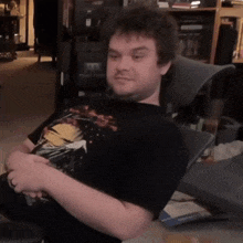 a man wearing a black shirt with a picture of iron man on it is sitting in a chair