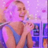 a woman in a blue tank top is sitting in front of a shelf with a purple light coming out of her mouth .