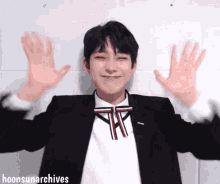 a young man in a suit and bow tie is waving his hands