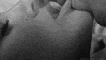 a black and white photo of a man and woman kissing each other .
