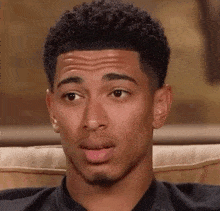 a young man sitting on a couch making a face
