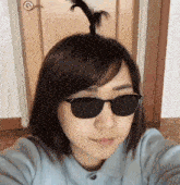 a woman wearing sunglasses and a ponytail takes a selfie