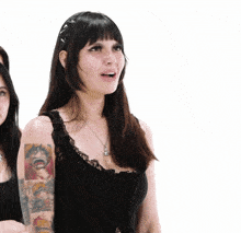 a woman with tattoos on her arms is wearing a black tank top