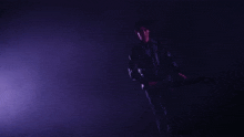 a person playing a violin in a dark room with a purple light behind them