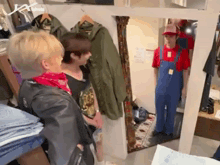a man in overalls is standing in front of a mirror in a store .