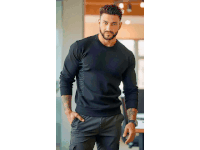 a man with a beard wearing a black sweater and cargo pants