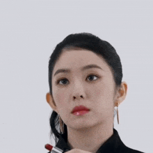 a woman with black nails is holding a red lipstick in her hand
