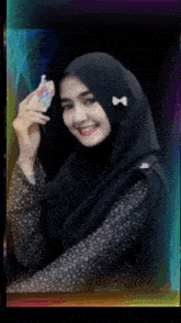a woman wearing a black hijab is smiling while holding a phone case