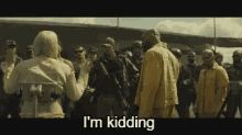 a group of people are standing in a line and a woman is standing in front of them saying i 'm kidding .