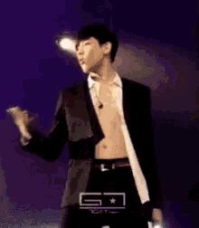 a man in a suit is dancing on a stage without a shirt .