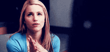a woman in a blue sweater is clapping her hands together