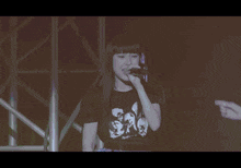 a woman singing into a microphone with a purple background