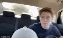 a young man sitting in the back seat of a car