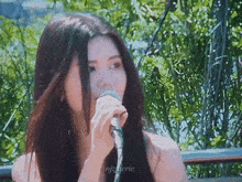 a woman with long hair singing into a microphone with the letters nf on the bottom right