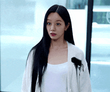 a woman is wearing a white cardigan and a white tank top