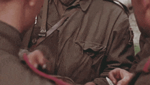 a man in a military uniform holds a piece of paper in his pocket