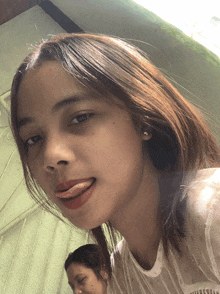 a girl with her tongue hanging out is wearing a white shirt with the word pink on it