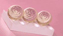 three cupcakes with pink frosting and sprinkles on a white plate