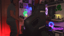 a man is standing in front of a kaiser gaming chair