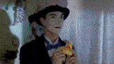 a man in a top hat and bow tie is holding a rubber duck in his hands .
