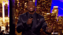 a man in a black suit stands in front of a microphone with nbc written on the bottom