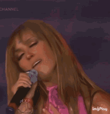 a woman is singing into a microphone with her mouth open