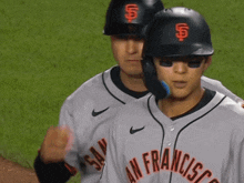 two baseball players from san francisco are standing on the field