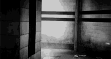 a black and white photo of a dark room with a brick wall .