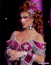 a drag queen in a pink and silver outfit with stars on the top
