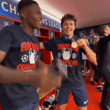 two soccer players in a locker room wearing shirts that say europa champions league