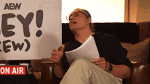 a man sitting in front of a sign that says aew on it