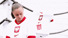 a woman wearing a white shirt with the number 100 on the back