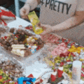a person wearing a shirt that says pretty is standing in front of a table filled with candy .
