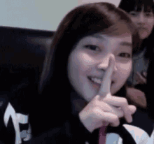 a woman is sitting on a couch with her finger on her nose .