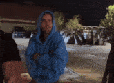 a man wearing a blue hoodie is standing in a parking lot