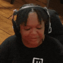 a woman wearing headphones is making a funny face while sitting on a wooden floor .
