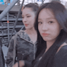 two women are standing next to each other in front of stairs and looking at the camera .