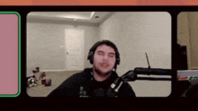 a man wearing headphones stands in front of a microphone in a room .