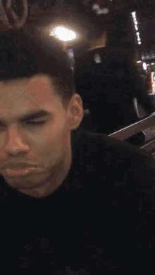 a close up of a man 's face with his eyes closed and a black shirt on .