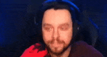 a man with a beard wearing headphones and making a funny face .
