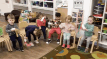a group of children are sitting on chairs in a room with a rug that says t on it