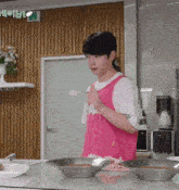 a man in a pink apron is standing in a kitchen with a sign above him that says holli