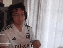 a man wearing headphones and a white adidas shirt is dancing in a room .