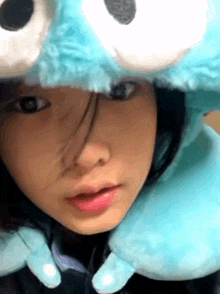 a girl wearing a cookie monster costume and a blue pillow around her neck .