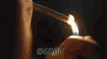 a hand holding a stack of money with the number 6000 written on it