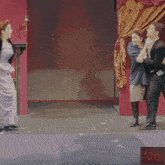a woman in a purple dress is standing next to a man in a tuxedo with the letter i in front of them
