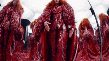 a woman with red hair is standing in front of a mirror in a red dress