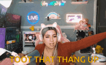 a woman wearing headphones and a cat headband says " toot that thang up "