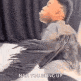 a person is sitting on a bed with a blanket on their back and says nah you hung up